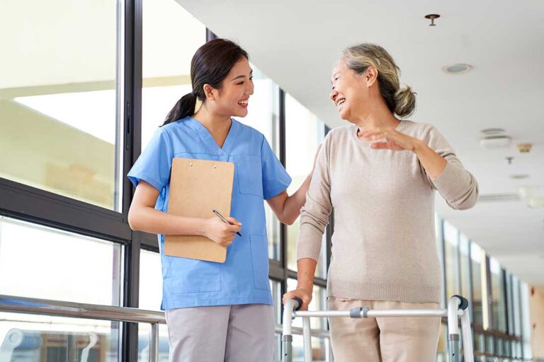 Resident choosing clothing with a caregiver in a bright assisted living apartment.