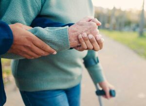 Older resident choosing clothing with a caregiver in a bright, private assisted living room.